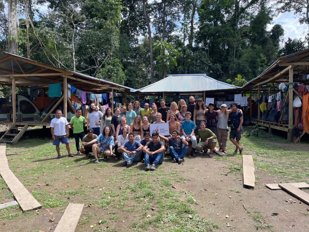 Large group of people posing for a photo in front of a camp in the Ecuadorian Amazon rainforest