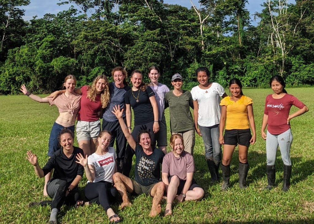 A group of women pose for the camera with their arms around each other in a field.